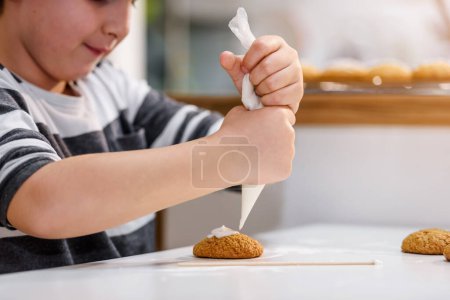Photo for Cute little boy decorating cookies with icing - Royalty Free Image