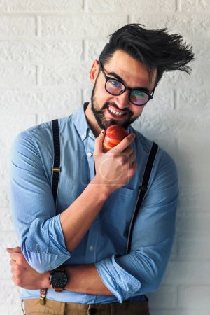 Téléchargez les photos : Jeune bel homme mangeant de la pomme - en image libre de droit