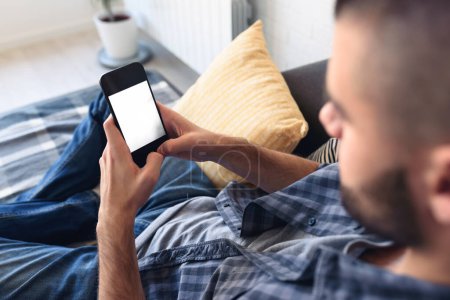 Photo for Man using mobile phone while sitting on sofa at home - Royalty Free Image