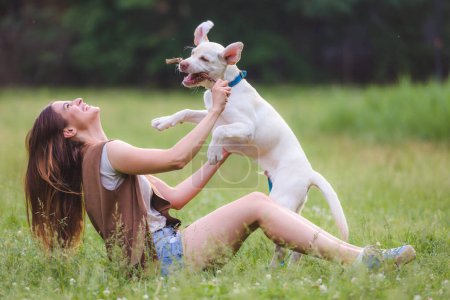 Téléchargez les photos : Jeune femme jouant avec la mignonne Labrador Retriever dans un parc public. Chien meilleur ami. - en image libre de droit