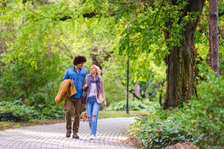 Téléchargez les photos : Jeune couple joyeux marchant dans le parc - en image libre de droit