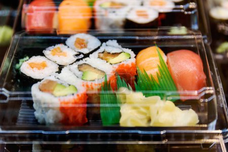Téléchargez les photos : Gros plan de sushi dans une boîte en plastique sur la table. sushi et livraison concept de nourriture. - en image libre de droit