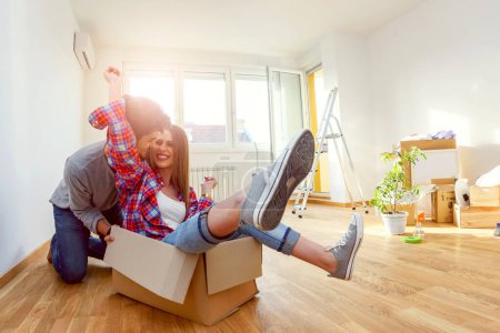 Foto de Feliz joven pareja moviéndose en casa nueva desempacando cajas, divirtiéndose - Imagen libre de derechos