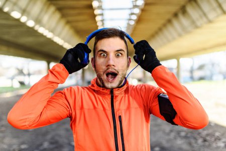 Téléchargez les photos : Man Runner criant sous le pont dans la ville et écoutant de la musique - en image libre de droit