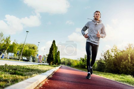 Photo for Man jogging in the morning out on the race track - Royalty Free Image