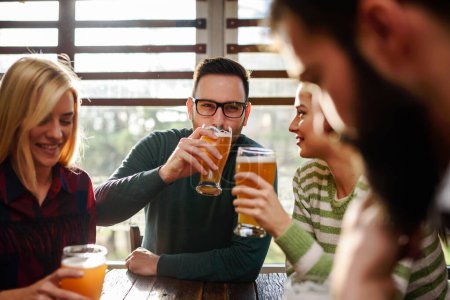 Photo for Group of young friends in bar drinking beer toasting - Royalty Free Image