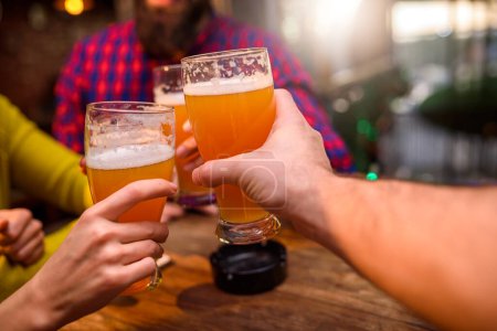 Foto de Grupo de amigos bebiendo cerveza en el pub - Imagen libre de derechos