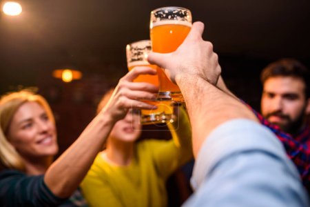 Téléchargez les photos : Groupe d'amis buvant de la bière au pub - en image libre de droit