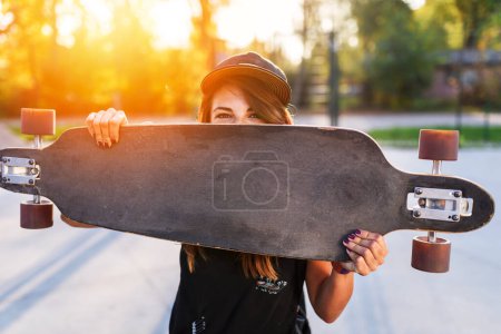 Photo for Cute urban girl holding longboard in skate park - Royalty Free Image