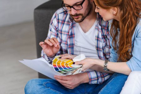 Foto de Feliz pareja eligiendo colores para pintar paredes en nuevo apartamento - Imagen libre de derechos