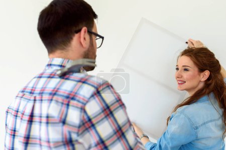 Téléchargez les photos : Couple dans un appartement vide mesurant les murs. Activités après déménagement et rénovation. - en image libre de droit
