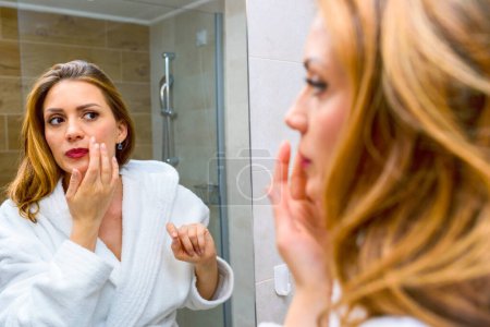 Téléchargez les photos : Belle jeune femme se préparer, regarder miroir dans la salle de bain - en image libre de droit
