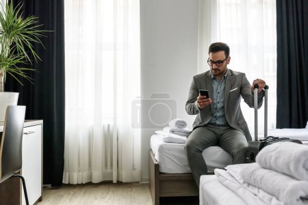 Téléchargez les photos : Jeune homme avec une valise dans la chambre d'hôtel - en image libre de droit