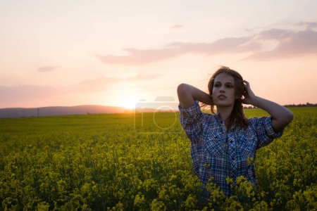 Téléchargez les photos : Belle femme posant sur le champ de canola au coucher du soleil - en image libre de droit