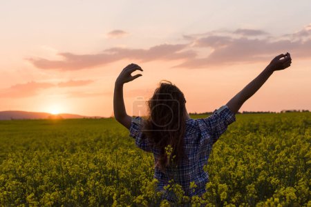 Photo for Beautiful woman posing on canola field at sunset - Royalty Free Image