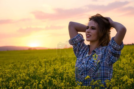 Photo for Beautiful woman posing on canola field at sunset - Royalty Free Image