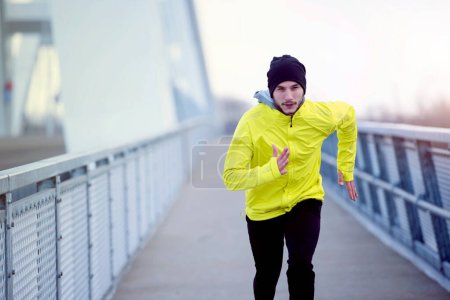 Téléchargez les photos : Homme en forme attrayant courir rapidement le long du grand pont moderne. Exercice, Jogging, Sport, Hiver. Athlète masculin courir. - en image libre de droit