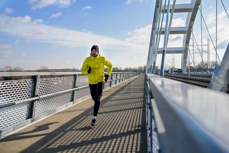 Photo for Young man jogging on the bridge in the city - Royalty Free Image
