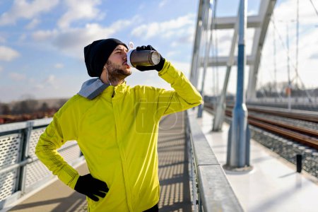 Foto de Joven atleta hombre beber agua - deshidratante durante el ejercicio al aire libre. - Imagen libre de derechos