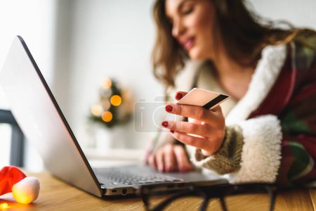 Téléchargez les photos : Jeune femme utilisant un ordinateur portable à la maison faisant des achats en ligne - en image libre de droit