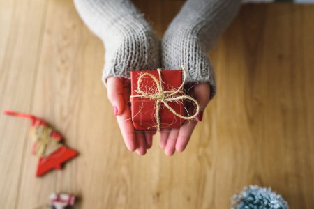 Téléchargez les photos : Mains de femme tenant cadeau de Noël sur fond en bois - en image libre de droit