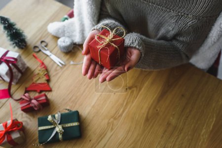 Foto de Manos de mujer sosteniendo regalo de Navidad sobre fondo de madera - Imagen libre de derechos
