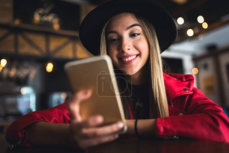 Téléchargez les photos : Jeune femme avec téléphone portable dans le café - en image libre de droit
