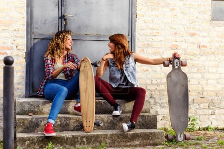 Photo for Skate girls sitting in the street hanging out - Royalty Free Image