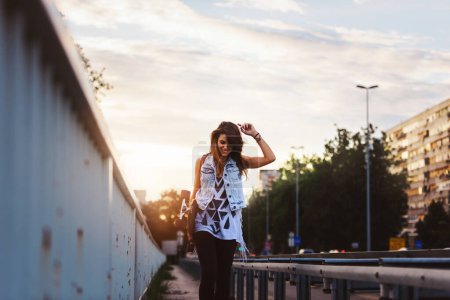 Téléchargez les photos : Mignonne fille urbaine tenant longboard dans skate park - en image libre de droit