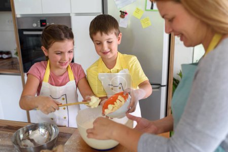 Photo for Mother, daughter and son cooking pastry together, working with dough - Royalty Free Image