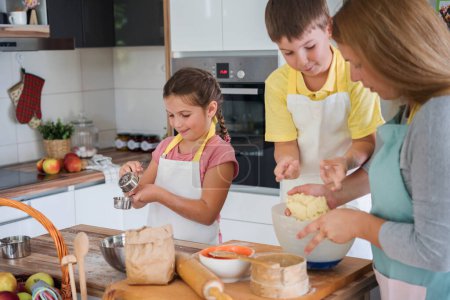 Téléchargez les photos : Mère, fille et fils cuisson pâtisserie ensemble, travailler avec de la pâte - en image libre de droit