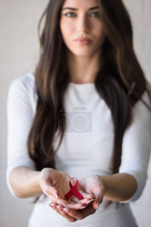 Photo for Woman holding red ribbon with aids awareness symbol - Royalty Free Image