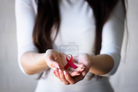 Photo for Woman holding red ribbon with aids awareness symbol - Royalty Free Image