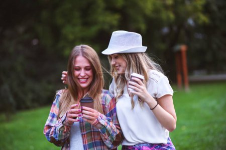 Photo for Two young women walking in green park. Student girls talking. Best friends - Royalty Free Image