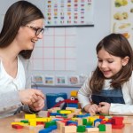 teacher and child playing with toy building blocks