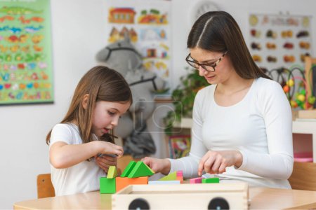 Photo for Teacher and child playing with toy building blocks - Royalty Free Image