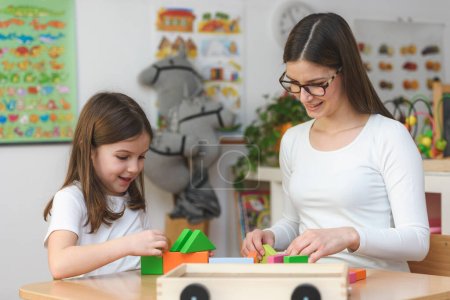 Photo for Teacher and child playing with toy building blocks - Royalty Free Image