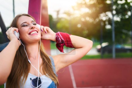 Téléchargez les photos : Jeune femme écoutant de la musique avec écouteurs - en image libre de droit