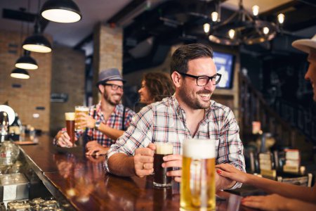 Foto de Amigos alegres pasar tiempo en el bar, beber cerveza - Imagen libre de derechos