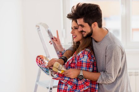 Téléchargez les photos : Couple choisir les couleurs pour la peinture des murs dans le nouvel appartement - en image libre de droit
