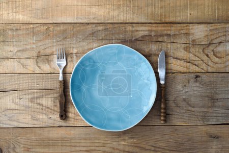 Téléchargez les photos : Couteau à plaque bleue et fourchette sur table rustique en bois. Fond de restaurant - en image libre de droit