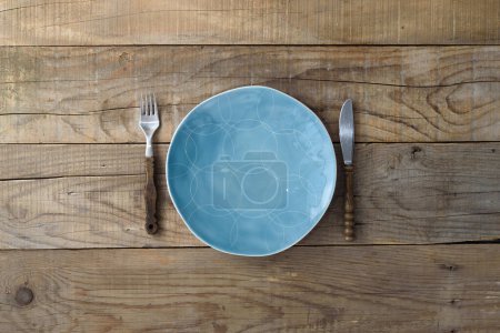 Téléchargez les photos : Couteau à plaque bleue et fourchette sur table rustique en bois. Fond de restaurant - en image libre de droit