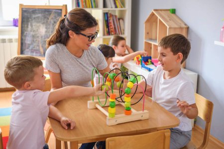 Photo for Preschool teacher with children playing with colorful wooden didactic toys at kindergarten - Royalty Free Image