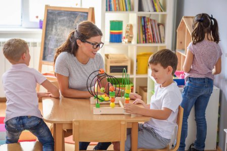 Téléchargez les photos : Professeur préscolaire avec des enfants jouant avec des jouets didactiques en bois colorés à la maternelle - en image libre de droit