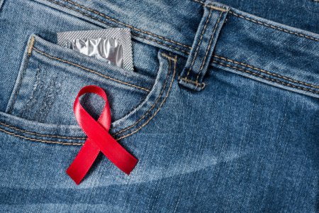Photo for Red ribbon over blue denim with condom in pocket - Royalty Free Image
