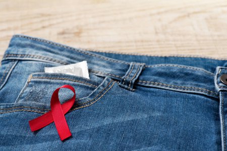 Photo for Red ribbon over blue denim with condom in pocket - Royalty Free Image