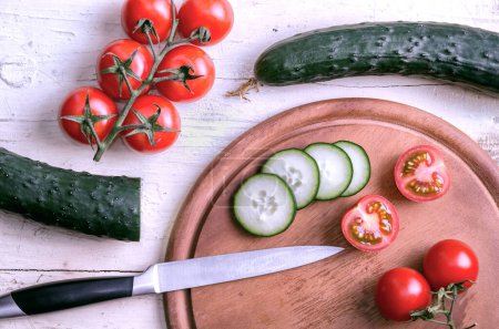 Photo for Cucumber and Tomatoes Cut With Kitchen Knife on White Old Table - Royalty Free Image