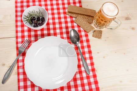 Téléchargez les photos : Table de taverne de nappe rouge à carreaux avec plaque et tasse de bière - en image libre de droit