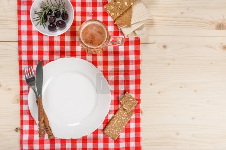 Téléchargez les photos : Table de taverne de nappe rouge à carreaux avec plaque et tasse de bière - en image libre de droit