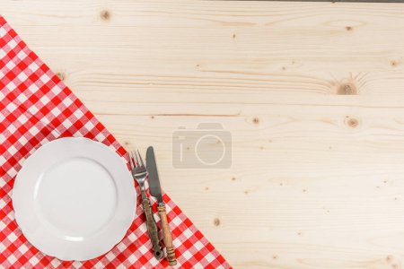 Foto de Mesa de madera con tenedor de placa de mantel rojo a cuadros y cuchillo - Imagen libre de derechos